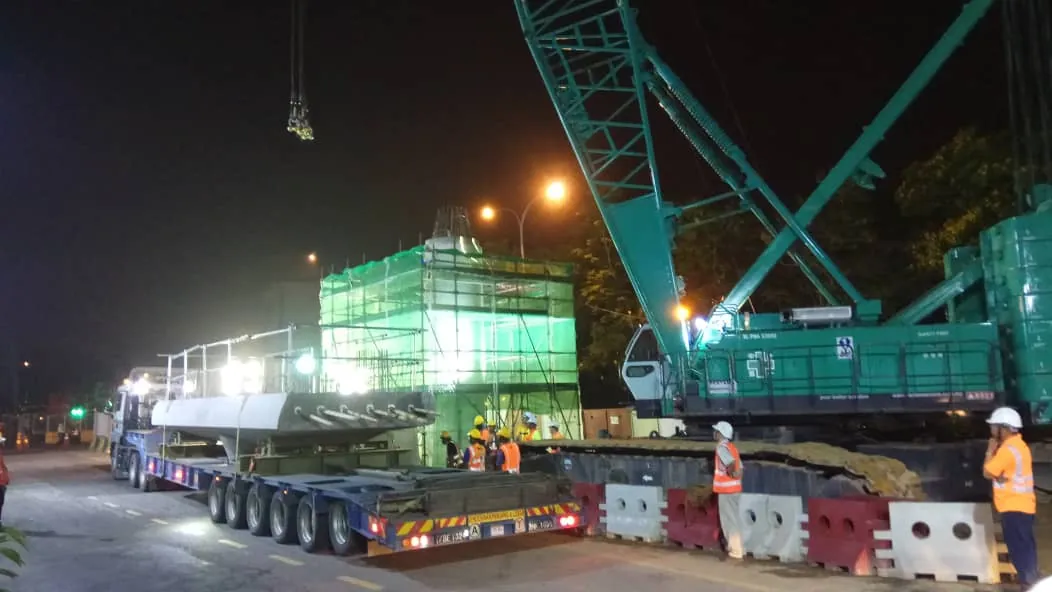 Kobelco CKE2500 crawler crane lifting an LRT3 pier cap at night
